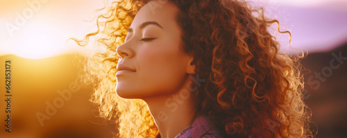 Close up sunset portrait of attractive woman with closed eyes and sun in back light, Dreaming and enjoying feeling concept lifestyle emotion, Serene female people outdoor with curly hair