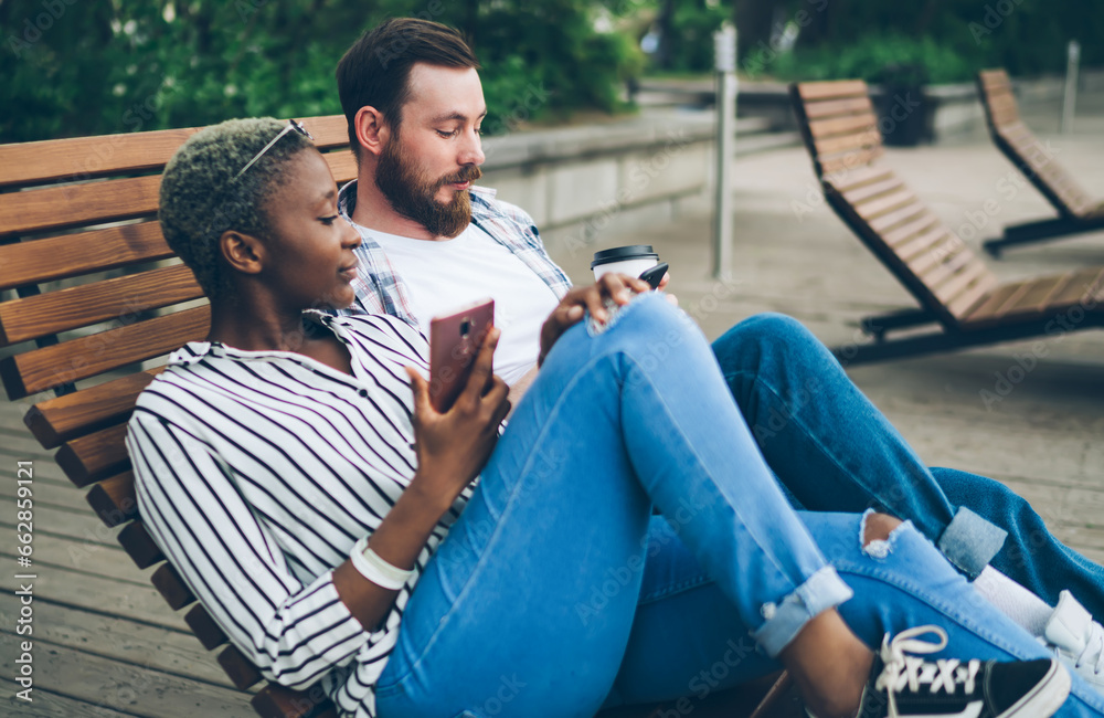 Peaceful couple chilling on street bench with devices