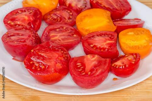 Halves of red and yellow tomatoes on dish, side view