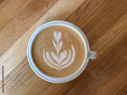 A cup of coffee latte on a wooden table. A mug of flat white coffee, latte, cappuccino on a wooden background. Coffee art. Heart flower swan shape latte art