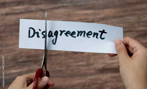 Scissors cutting word disagreement on paper