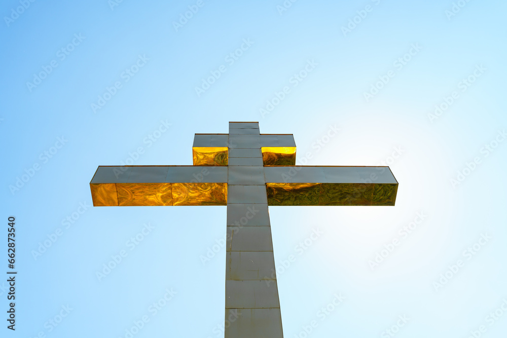 A huge golden cross on a mountain against the sky