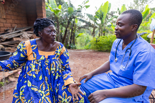 A doctor talks to his elderly patient during a home visit in an African village