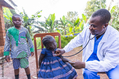 A pediatrician uses a stethoscope during a visit to children in a village in Africa