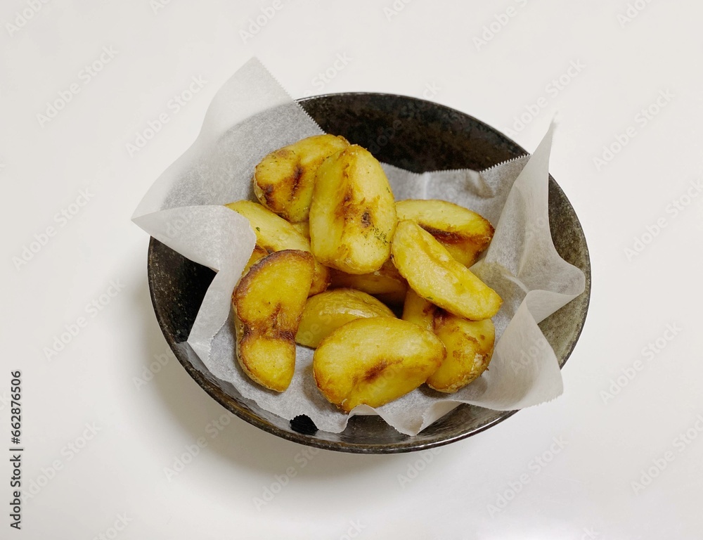 Wedge cut french fries in a black bowl Wedge cut french fries in a black bowl