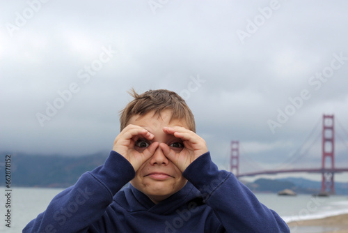 Photography Portrait of a 10-year-old handsome blond boy on the sandy beach of San Francisco on a cloudy day