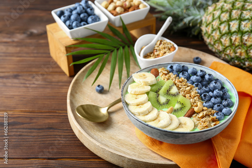 Tasty smoothie bowl with fresh fruits and oatmeal served on wooden table, space for text