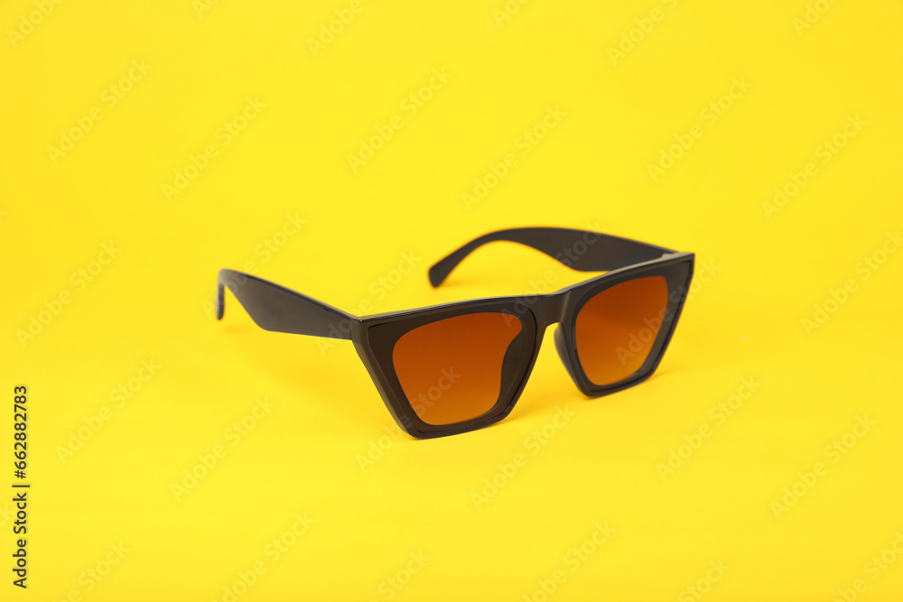 Stylish pair of sunglasses on yellow background Stylish pair of sunglasses on yellow background