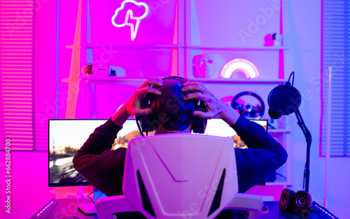 Back male game online streamer, caster, angry, losing, compete driving games, sitting in room with decorated neon light. Looking at computer.