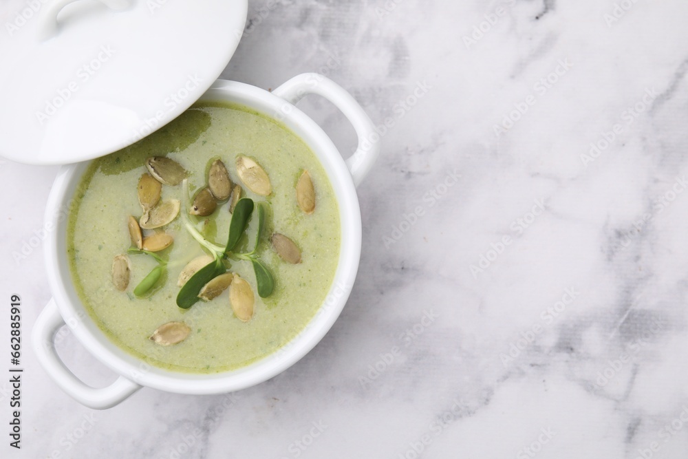 Delicious broccoli cream soup with pumpkin seeds on white marble table, top view. Space for text Delicious broccoli cream soup with pumpkin seeds on white marble table, top view. Space for text