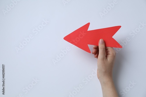 Fototapeta Naklejka Na Ścianę i Meble -  Woman holding red paper arrow on white background, top view. Space for text