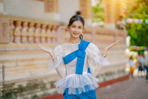Portrait of Asian women with khmer traditional dress stand in front of pagoda with beautiful art and architecture, they also smile and look at camera