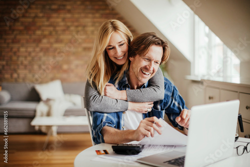 Happy young couple going over financials together at home
