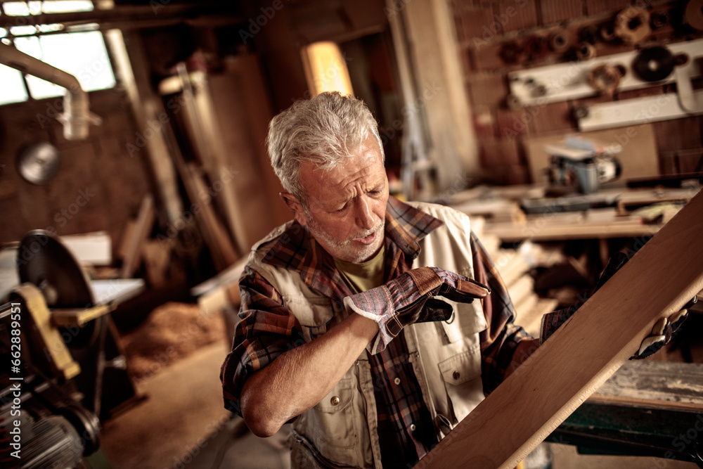 Senior male carpenter measuring wood in a carpentry shop Senior male carpenter measuring wood in a carpentry shop