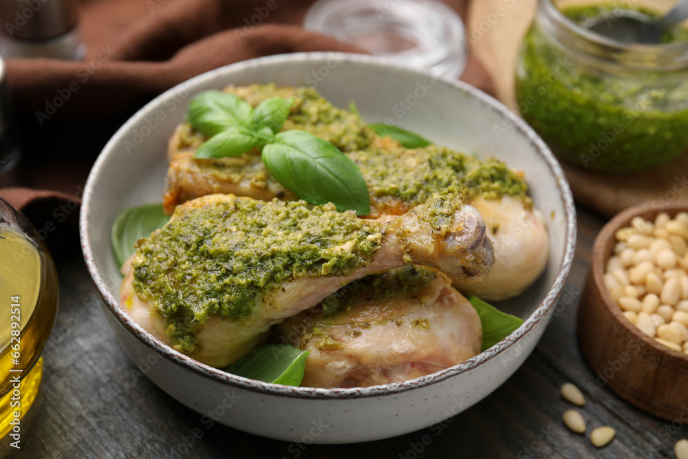 Delicious fried chicken drumsticks with pesto sauce and basil in bowl on table, closeup Delicious fried chicken drumsticks with pesto sauce and basil in bowl on table, closeup