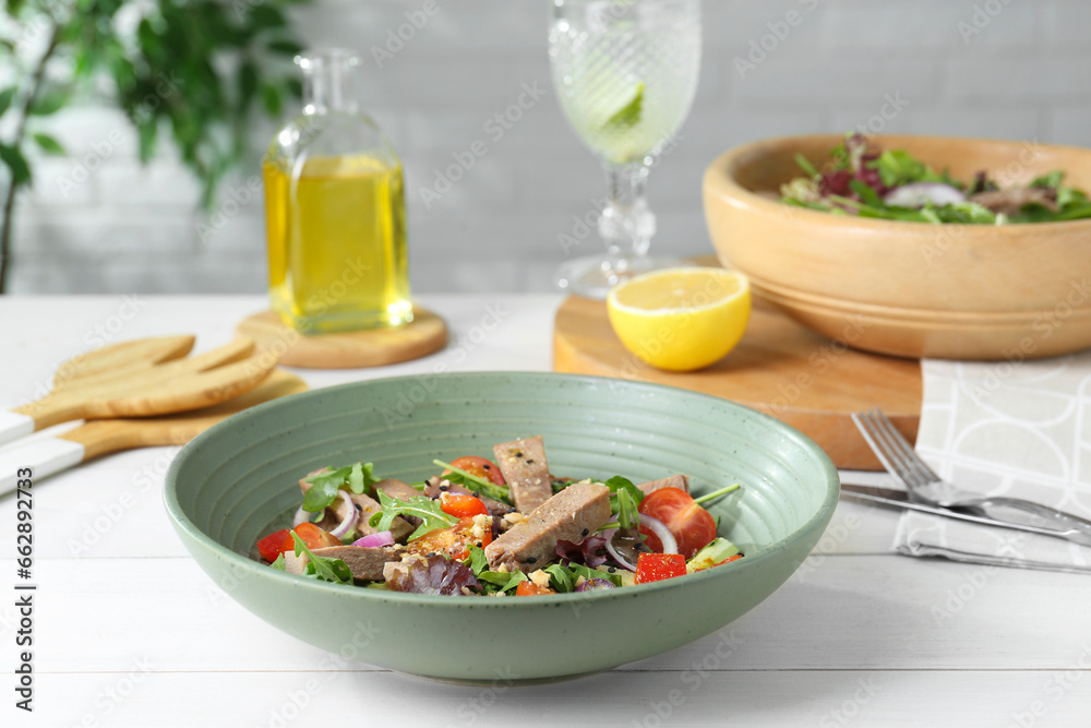 Delicious salad with beef tongue and vegetables served on white wooden table