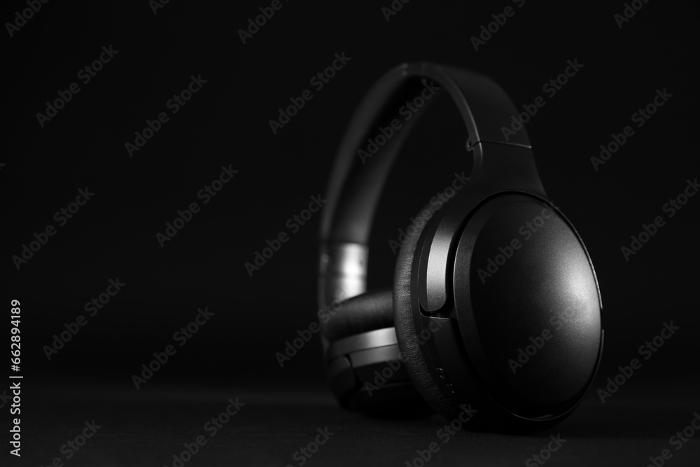 Modern wireless headphones on black background, space for text Modern wireless headphones on black background, space for text
