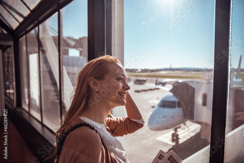 Happy young woman waiting for her flight at the airport photo