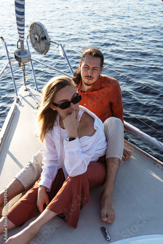 Young attractive couple relaxing on the sailboat during sailing in the sea