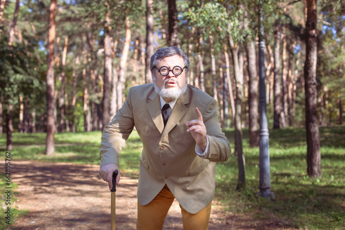 Funny old man with a stick. An elderly man with a walking stick with a funny face. The man has a funny face with a beard. photo