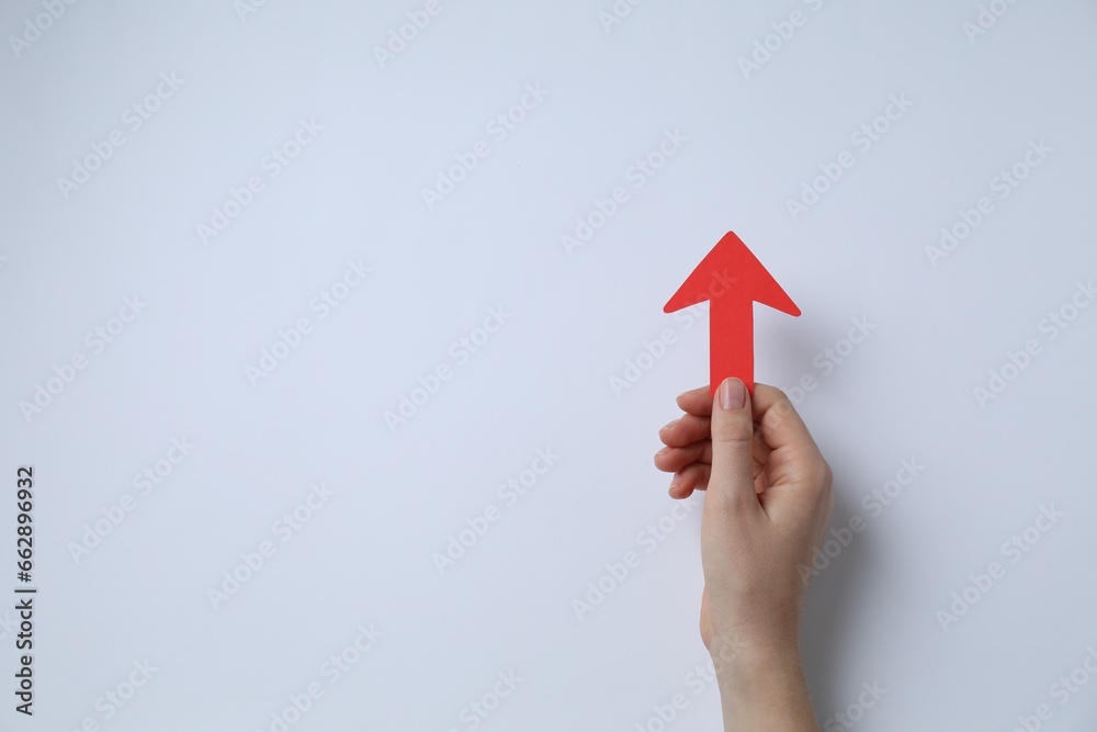 Woman holding red paper arrow on white background, top view. Space for text - obrazy, fototapety, plakaty 