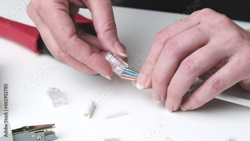 An engineer installs a new connector on a cable using a tool. Tool for crimping internet cable, cable and connectors on the desktop. photo