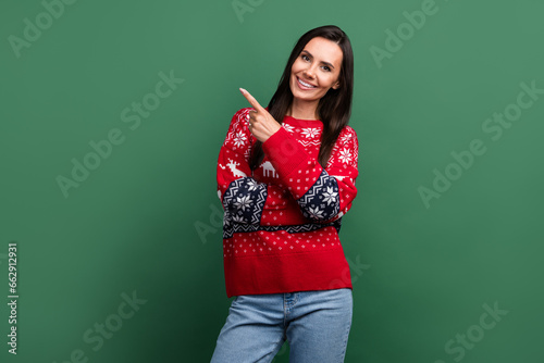 Photo of pretty positive girl indicate finger empty space x-mas ad offer isolated on green color background