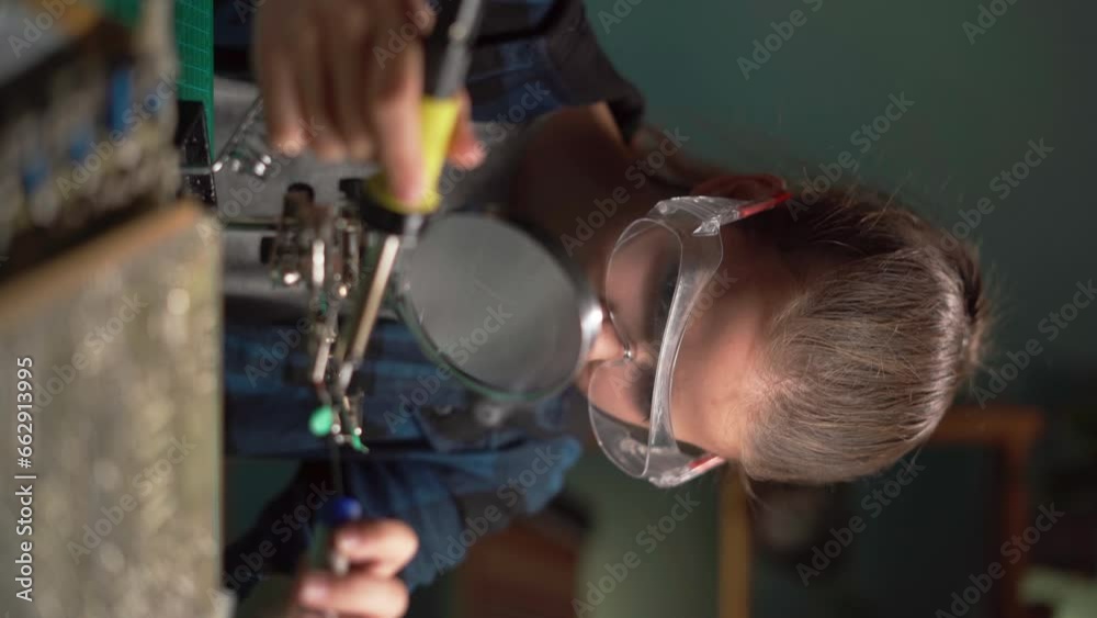 Teen girl with soldering iron at home. Repairing computer hardware engineering, technology and science concept. Teen girl with soldering iron at home. Repairing computer hardware engineering, technology and science concept.