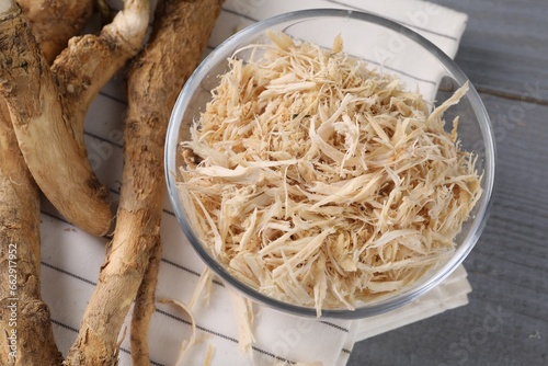 Grated horseradish and roots on grey wooden table, above view