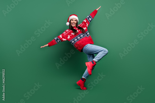 Full length photo of positive carefree woman santa elf wear ornament x-mas pullover hands wings plane fly isolated green color background