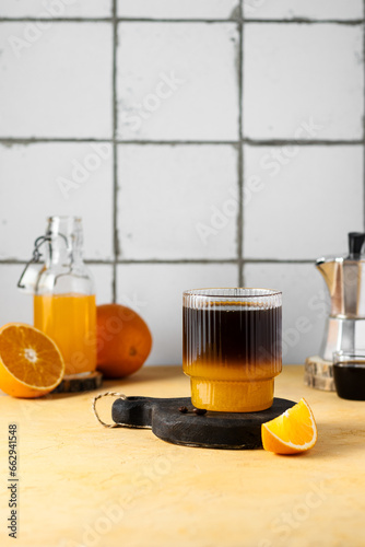 Warm bumble coffee. Autumn and winter caffeine drink with orange juice for cold weather. Vitamine C hot layred drink, white tile background. Copy space  photo