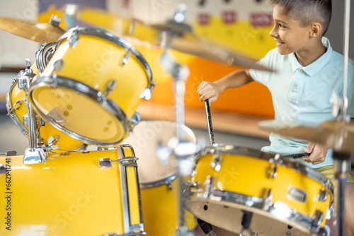 Little boy playing on a real drums, having fun while visiting a science museum