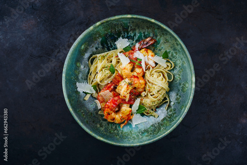 Traditional fried king prawns with Italian tagliatelli pasta and parmesan cheese served as top view on a design bowl with text space