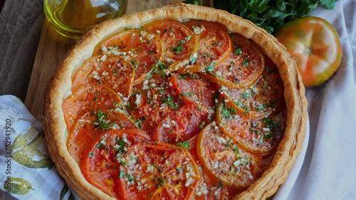 Round puff pastry pie tart with tomato. Rotate.