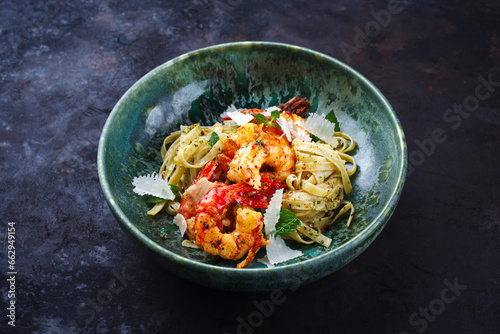 Traditional fried king prawns with Italian tagliatelli pasta and parmesan cheese served as close-up in a design bowl with text space