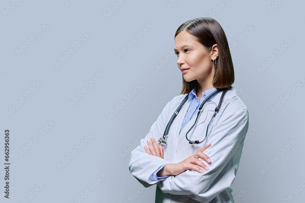 Young woman doctor looking in profile, copy space for advertising text image, grey background Young woman doctor looking in profile, copy space for advertising text image, grey background