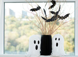 Halloween. Concept. Autumn holiday. Layout. Background.Two white ghosts and a black vase with dry branches and bats made of paper against the background of a window.