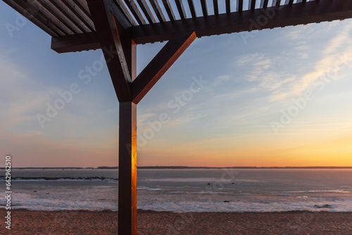 Coastal wooden sunshade in the evening, winter beach landscape