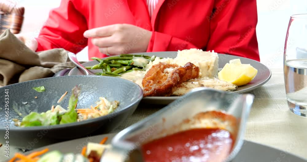 Mid-height view captures a woman in a red coat savoring a delicious fish and salad dish at an outdoor restaurant, a delightful dining experience Mid-height view captures a woman in a red coat savoring a delicious fish and salad dish at an outdoor restaurant, a delightful dining experience