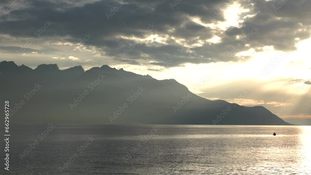 The sun sets behind the mountains above the lake. Evening in the mountains. Sunset on the lake among the Alps. the boat sails in the rays of the setting sun, 4k 59 fps The sun sets behind the mountains above the lake. Evening in the mountains. Sunset on the lake among the Alps. the boat sails in the rays of the setting sun, 4k 59 fps