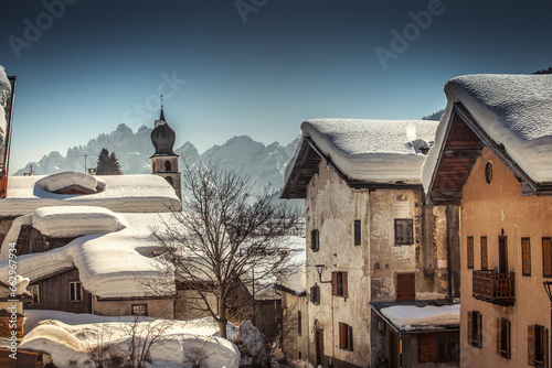Houses in small Dolomite village with snow-covered roofs. Val di Zoldo, Dolomites, Italy. Dramatic color effect