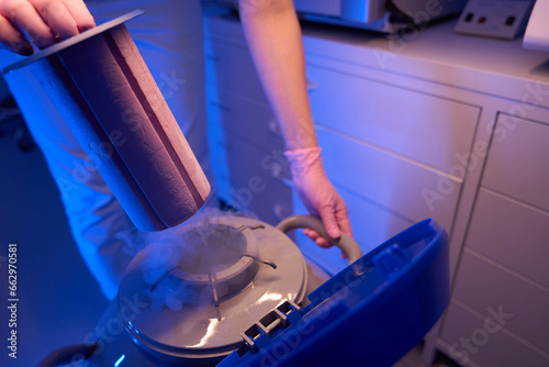 Laboratory researcher using cryogenic dewar for storage of biological specimens photo