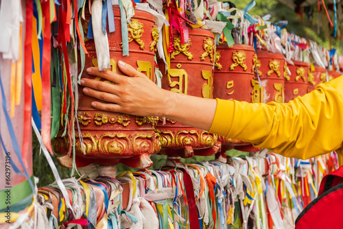 фотографія Person pilgrim female hand touching turning spinning Buddhist prayer wheel at Buddhist monastery