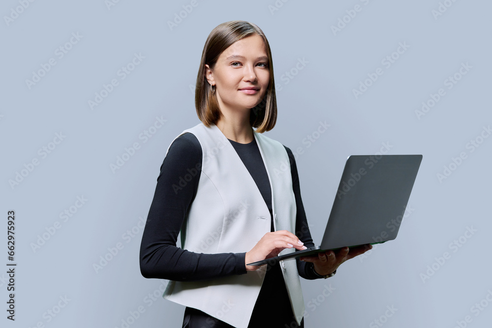 Smiling young business woman with laptop on grey studio background Smiling young business woman with laptop on grey studio background