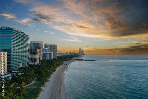 aerial shot of hotels, luxury condos and skyscrapers along the coastline at sunrise at Bal Harbour Beach, blue ocean water, silky sand and lush green trees and grass in Miami Beach Florida USA © Marcus Jones
