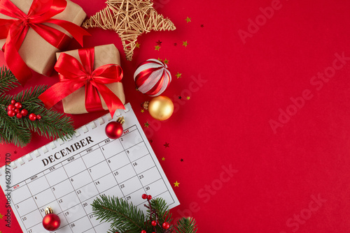 Prepare to spread love and happiness with thoughtful gifts. Top view flat lay of calendar, presents, fir branches, tree ornaments, shiny stars on red background with advert zone