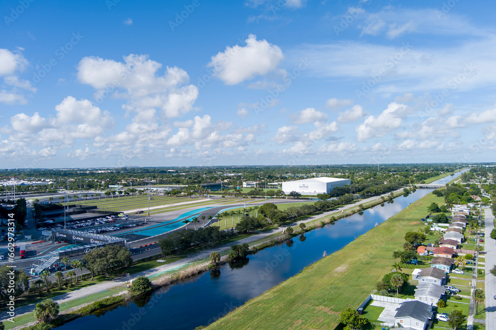 aerial shot of a river surrounded by lush green trees and grass, homes and parked cars with blue sky and clouds in Miami Florida USA