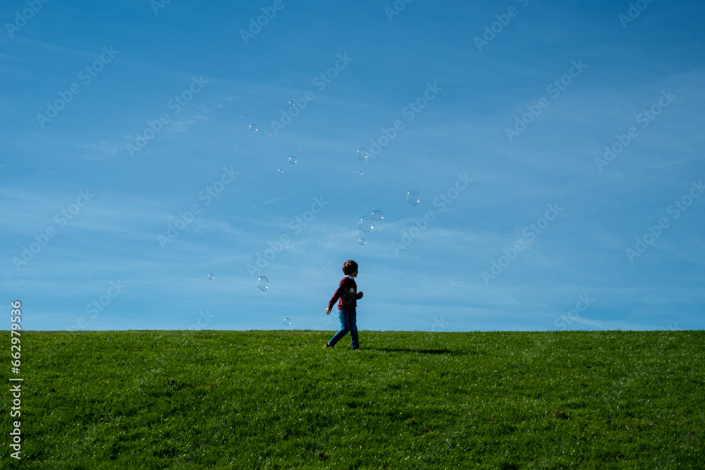 silhouette of a child on a hill playing with some soap bubbles in the sky silhouette of a child on a hill playing with some soap bubbles in the sky