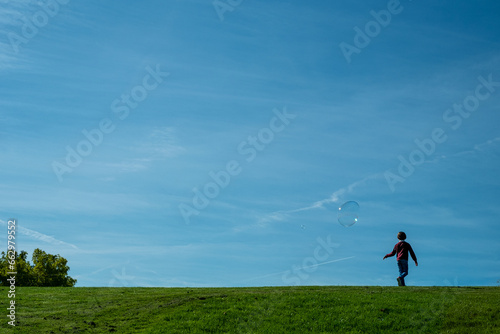 silhouette of a child on a hill playing with some soap bubbles
