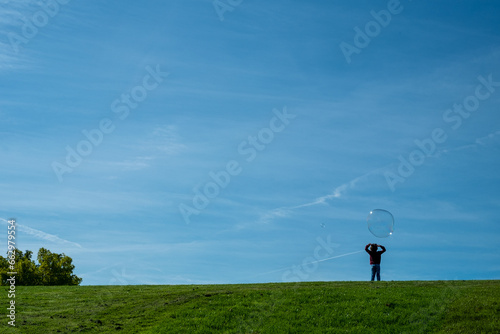 silhouette of a child on a hill playing with some soap bubbles
